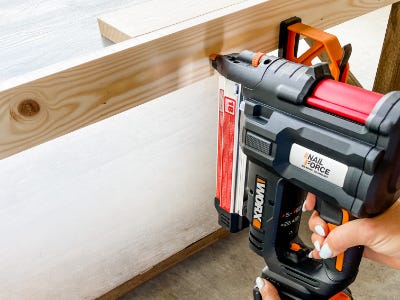using orange and black nail gun into wood piece
