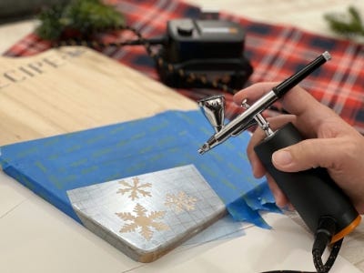 using airbrush to air brush paint onto snowflake with gold paint