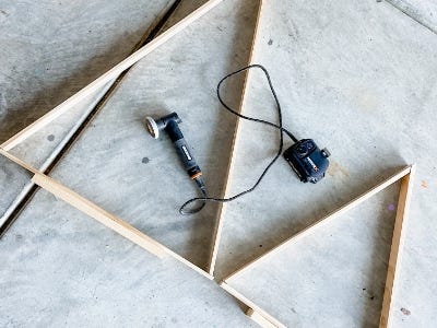 pieces of wood laid out in to the shape of 2 triangles next to the MakerX Angle grinder