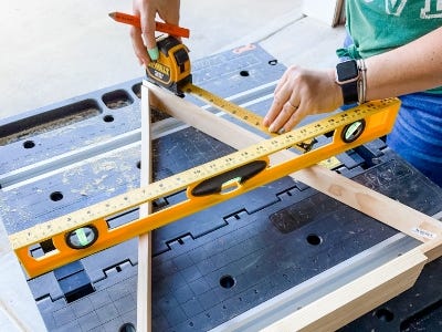 image of a person using a level and measuring tape to align the pieces of wood on the work table