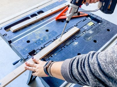 image of a person using the Worx Switchdriver to drill a hole into a piece of wood on the work table