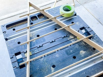 image of a person laying the wooden dowels on top of the larger wooden triangle on the work table