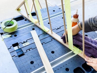 image of a person using painters tape to hold the glued wooden dowels in place