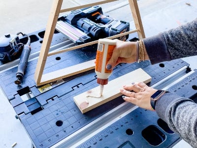 image of a person applying glue to the base of the wooden tree on top the work table with the MaklerX on the table next to it