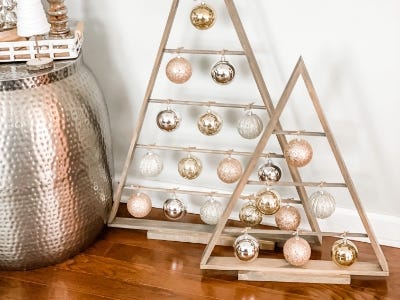 image of the two wooden trees on display with small ornament balls on the dowels next to copper Christmas decor