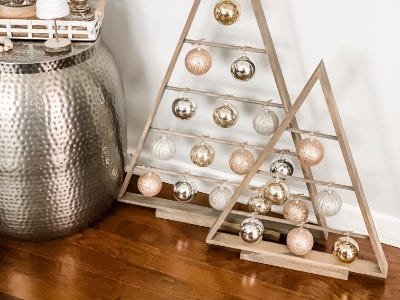 image of the two wooden trees on display with small ornament balls on the dowels next to copper Christmas decor 