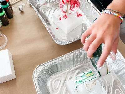 paint being poured from cup onto top of clear ornament