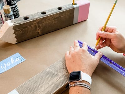 using pencil and ruler to mark guidelines on wood piece