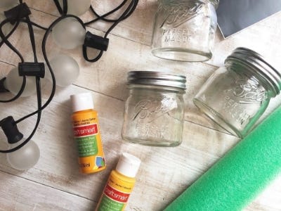 3 closed clear jars next to yellow green paint and rope lights