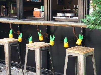 pineapple jars hanging underneath table on string behind multiple bar stools