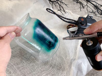 using airbrush to paint blue color over stencil on to glass