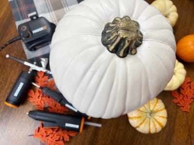 air brush and mini glue gun next to large white pumpkin