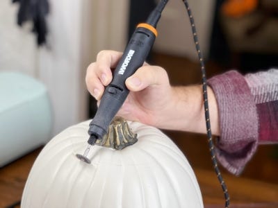 using rotary tool to cut along penciled line on white pumpkin