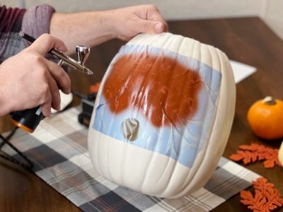 air brushing white pumpkin with stencil applied