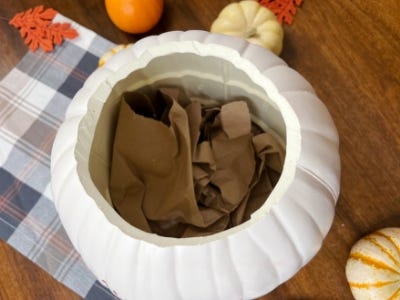 crumpled brown paper inside bottom of open white pumpkin