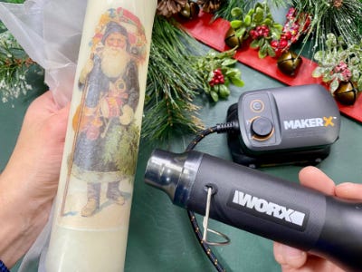 using heat gun to apply santa sticker to candle