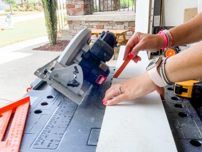 using pencil to mark guidelines on wood next to saw