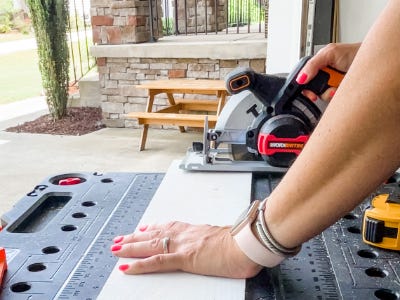 using saw to cut the edge of wood piece on top of worx worktable