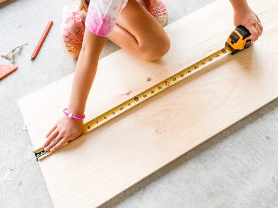 using measuring tape to measure on wood piece