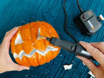 using rotary tool to cut out triangle eyes in pumpkin