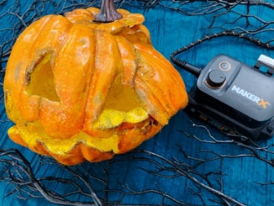 smashed pumpkin on blue cloth and sticks next to worx battery and charger