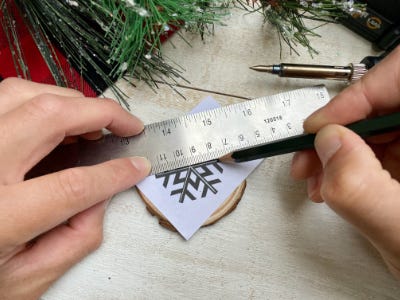 using a ruler and pencil to transfer snowflake too wood piece