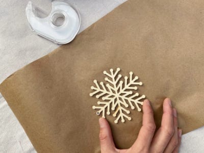 placing snowflake stencil on brown wrapping paper