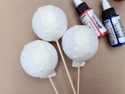 added tape to foam balls on sticks next to paint bottles