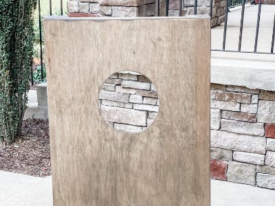 stain board standing upright in front of stone wall