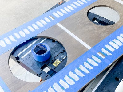 plywood board with blue painters tape and white paint on top of worktable