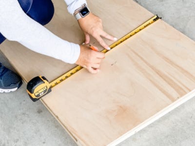 using measuring tape to measure height of plywood board