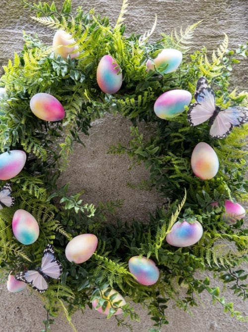 Image of tie dye Easter wreath hanging on wooden background