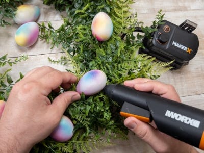 person gluing eggs onto the wreath with the makerx glue gun