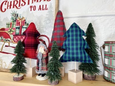 plush paid trees inserted into cube block standing next to wall and standing fake Christmas trees