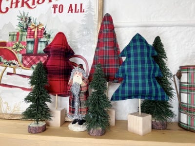 plush paid trees inserted into cube block standing next to wall and standing fake Christmas trees and santa