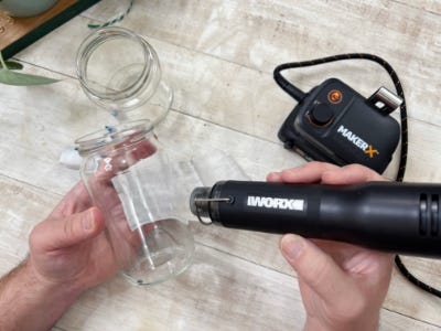 heat gun being used on jar to remove jars label is removed