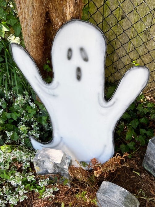 wooden ghost on the ground next to a tree