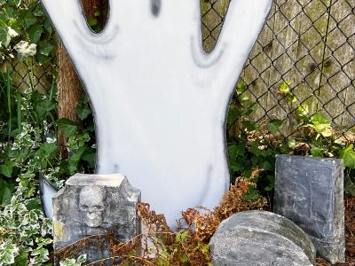 zoomed in ghost in garden next to tombstones and in front of fence