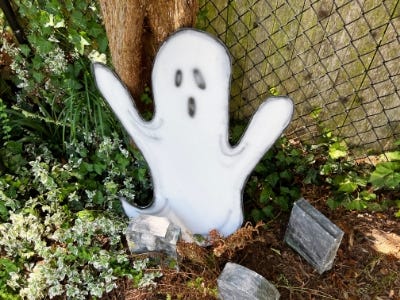top view of ghost in garden next to tombstones and in front of fence