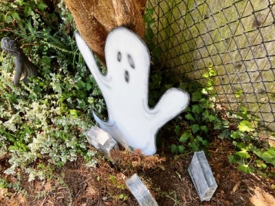 side view of ghost in garden next to tombstones and in front of fence