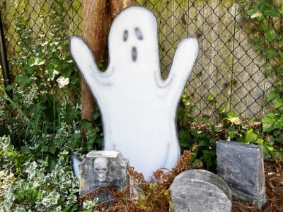 front of ghost in garden next to tombstones and in front of fence