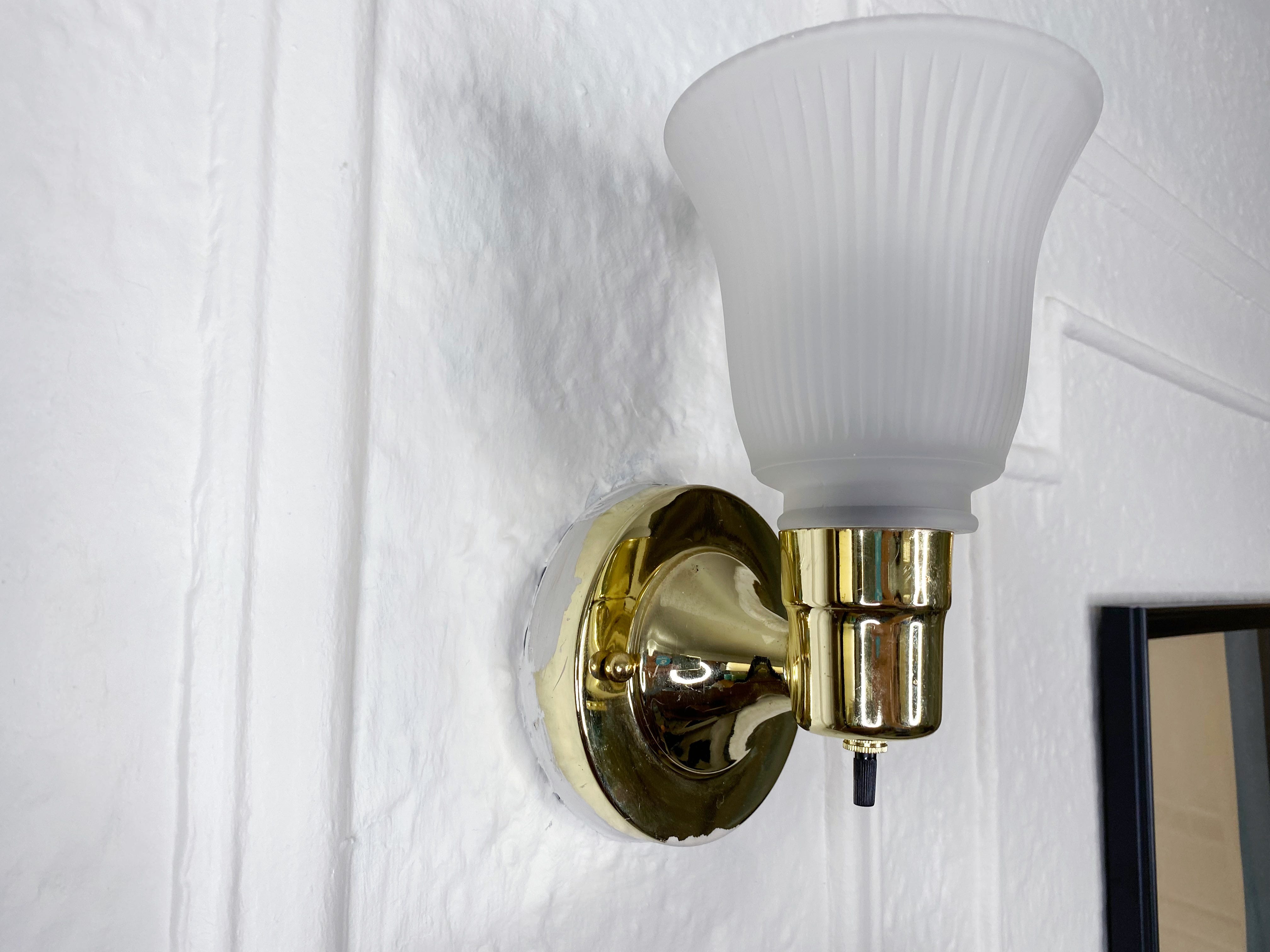 gold wall sconce hanging from white wall