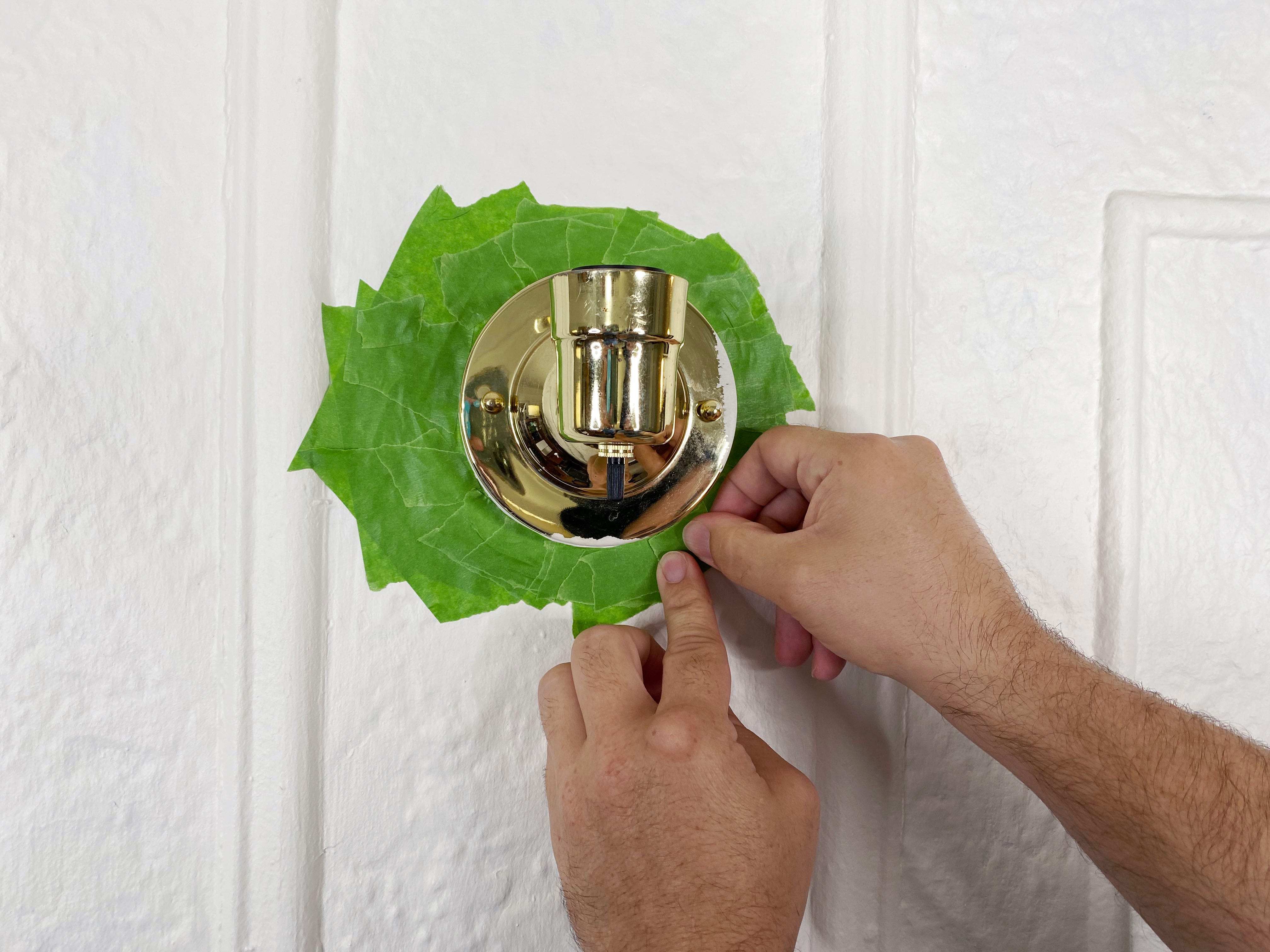 placing green painters tape around wall scone with no cover