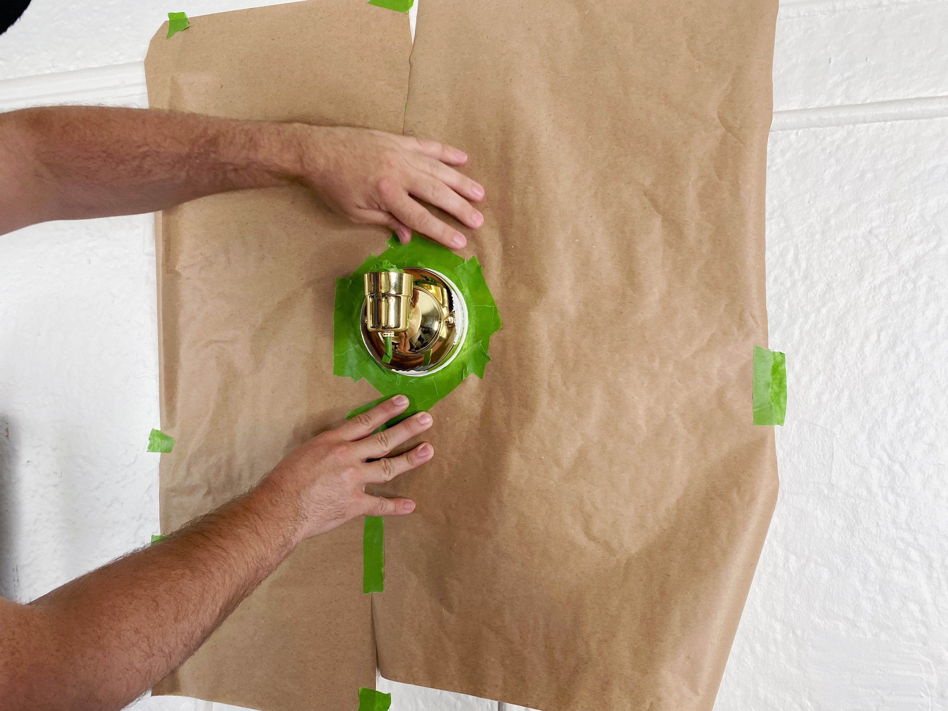 placing brown paper on top of green painter tape and around sconce