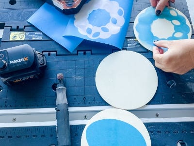 attaching stencils on to circle wood blocks next to rotary tool