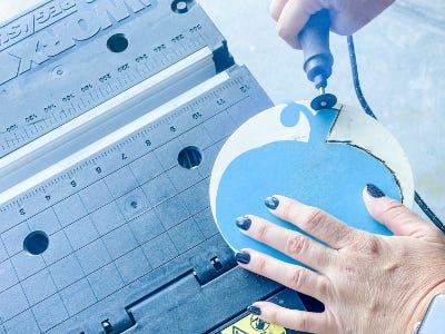 using the cutting rotary tool to cut wood around the wood stencil