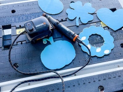 pumpkin, wreath, heart, egg, and four leaf clover tempaltes cut out next to rotary tool