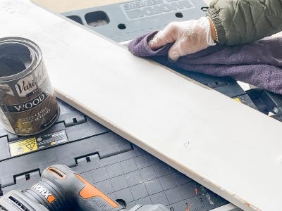 using towel to rub down the edges of the freshly painted wood piece