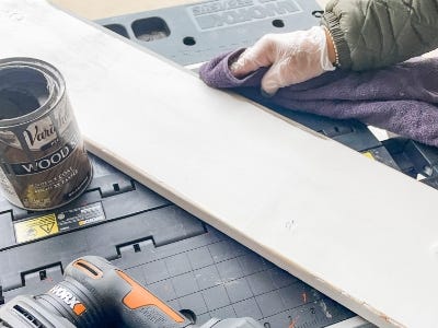 using towel to rub down the edges of the freshly painted wood piece