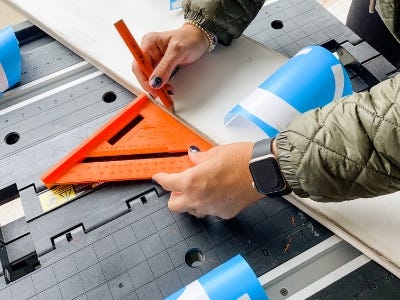 measuring the painted wood peice with stencils next to it